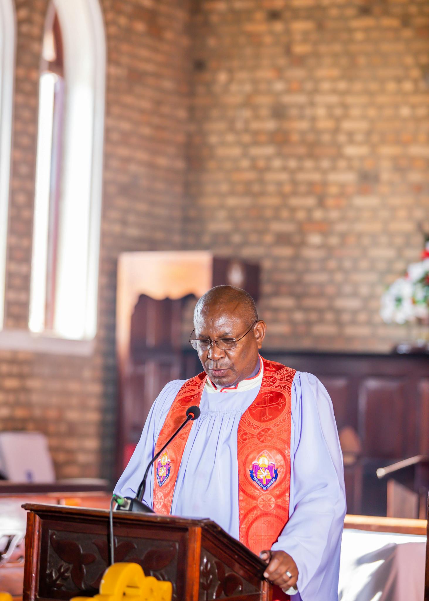 Religious leader in traditional attire delivering a sermon at a church podium.
